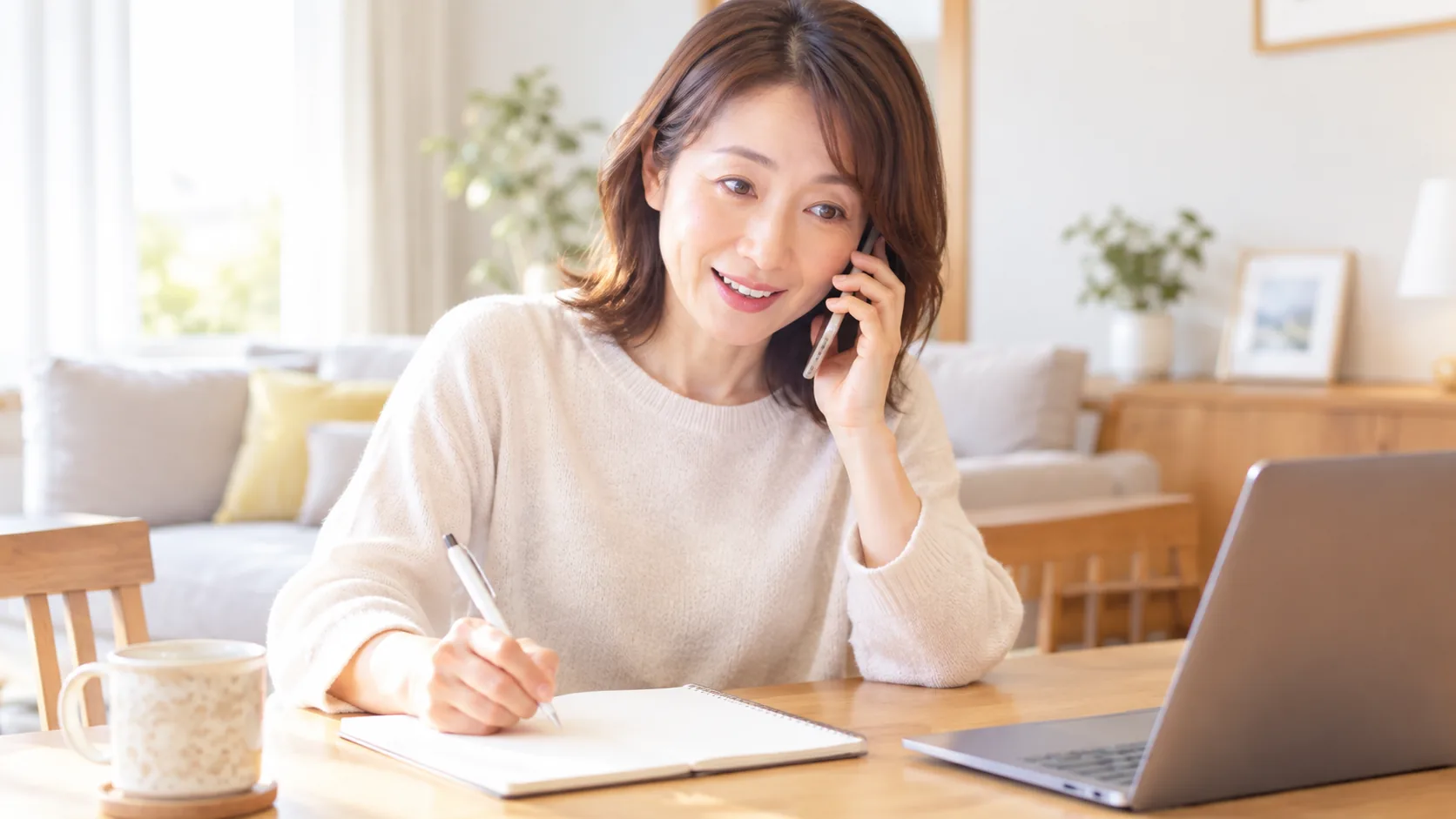 スマートフォンで問い合わせながら、ノートにメモを取っている女性